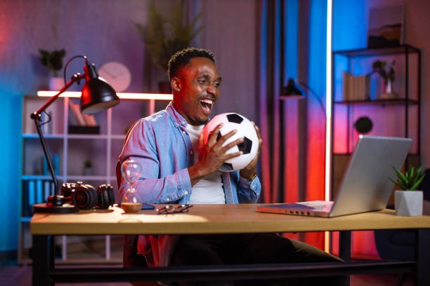 Jeune homme regardant l’IPTV sur son ordinateur portable dans le salon de sa maison.